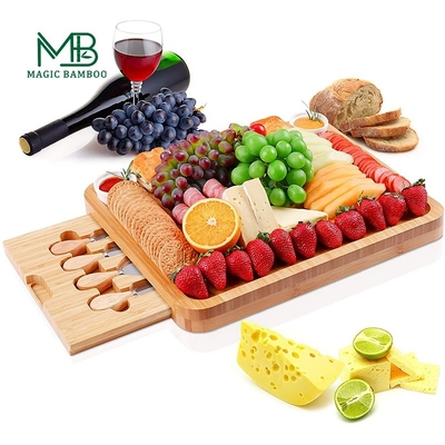 Une table de fromage en bambou rectangulaire avec des couverts et une assiette en céramique